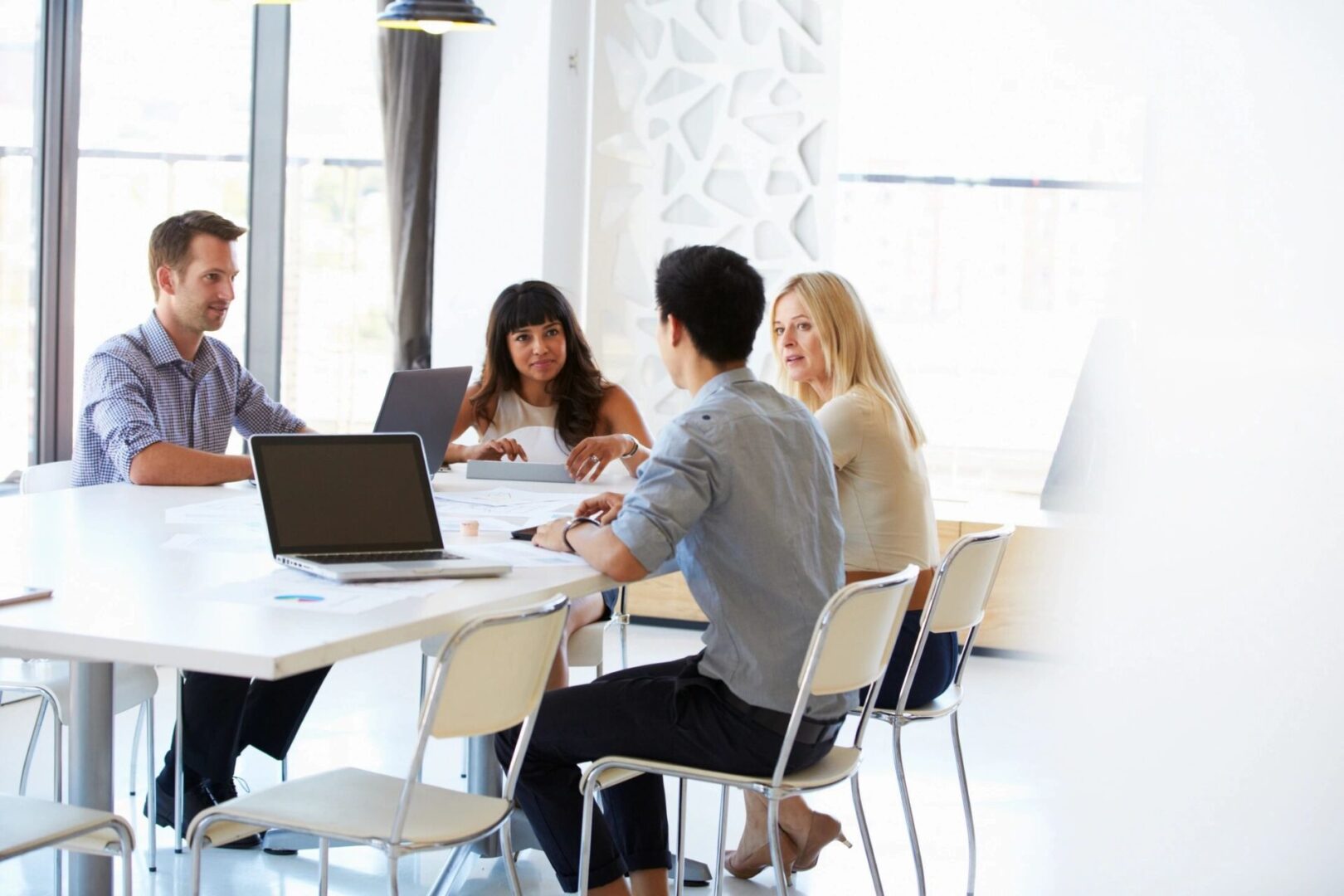 A group of people sitting at tables with laptops.